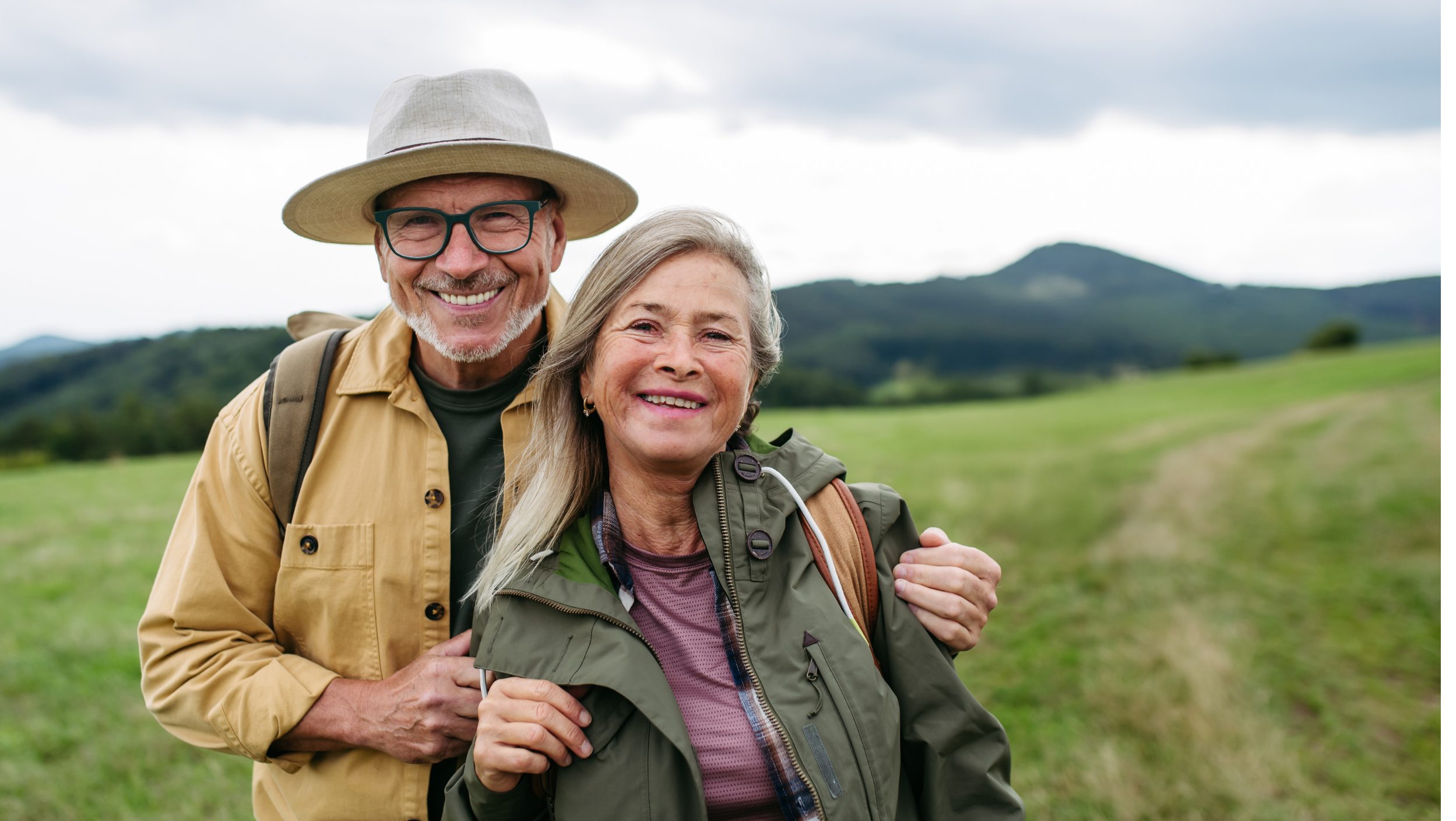 smiling couple in the outdours seemingly on an adventure