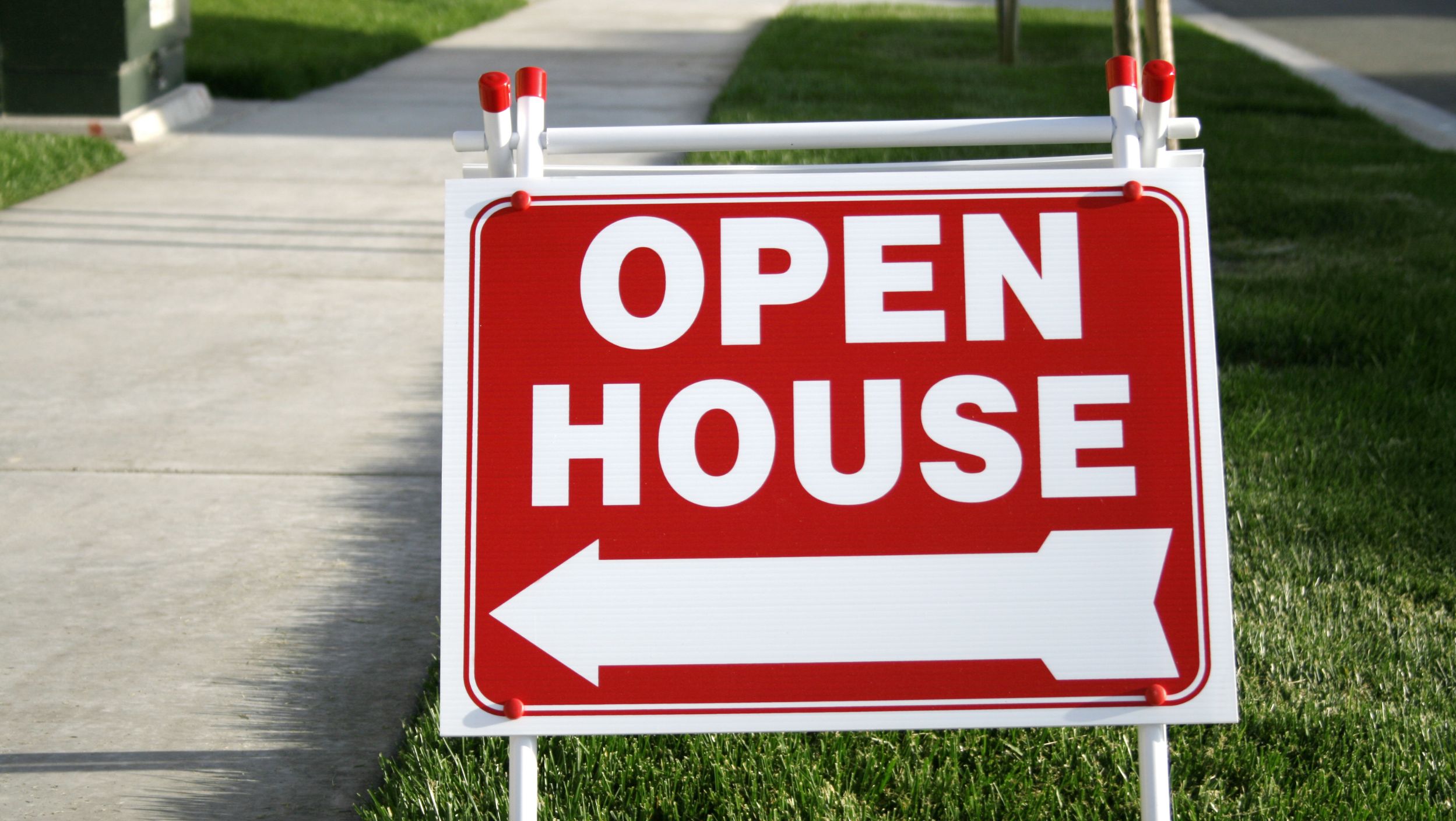 open house real estate sign outside a house on the sidewalk